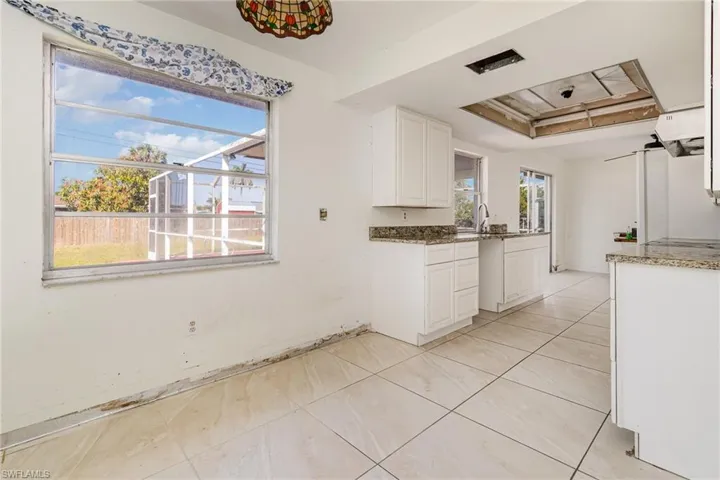 Kitchen featuring plenty of natural light, dark stone countertops, white cabinets, and a sink
