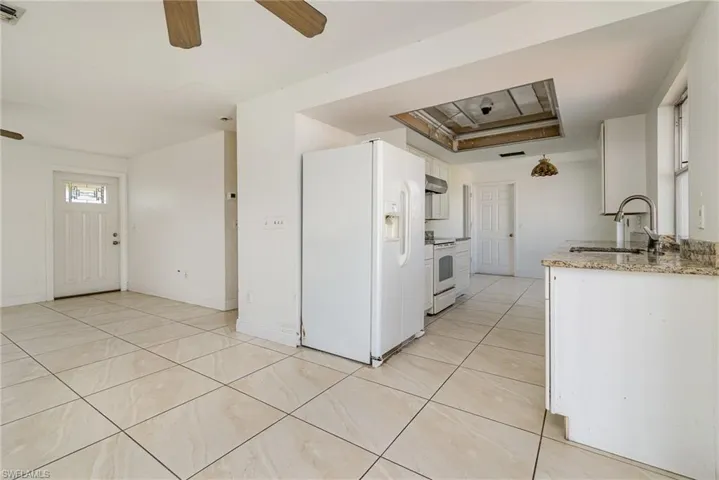 Kitchen featuring light tile patterned flooring, white appliances, a sink, a ceiling fan, and white cabinets