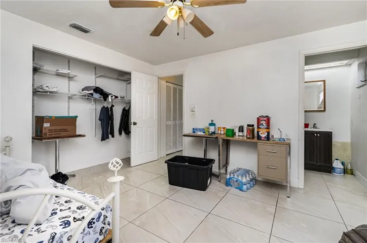 Bedroom featuring light tile patterned floors, ceiling fan, ensuite bathroom, visible vents, and a closet
