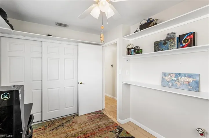 Office featuring built in shelves, ceiling fan and light tile patterned floors.
