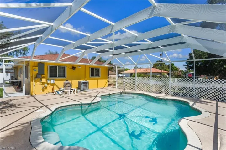 View of pool featuring patio surround, a sunroom, and screen enclosure.