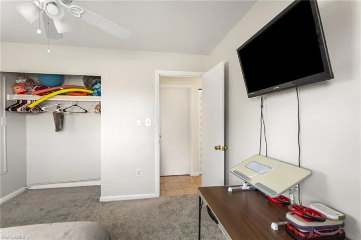 Bedroom with light colored carpet, ceiling fan, and light tile patterned floors