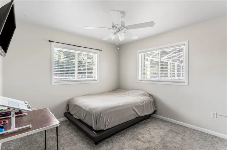 Carpeted bedroom featuring a ceiling fan and baseboards