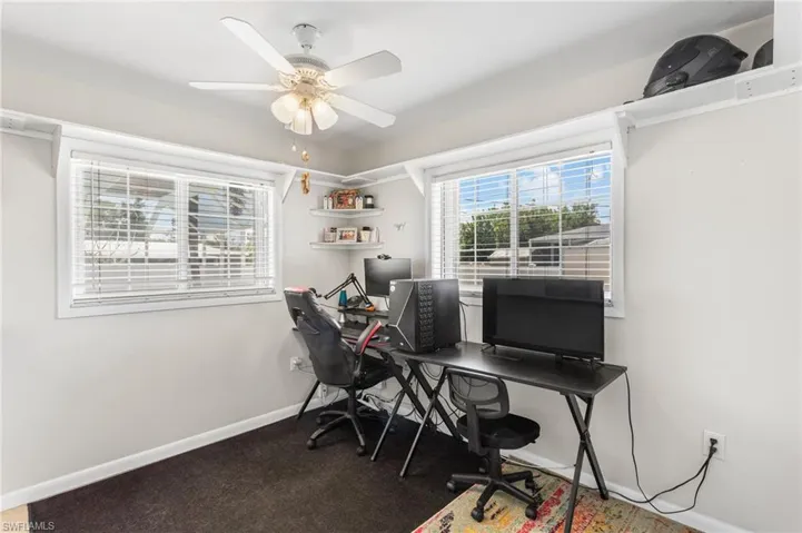 Carpeted home office featuring baseboards and ceiling fan