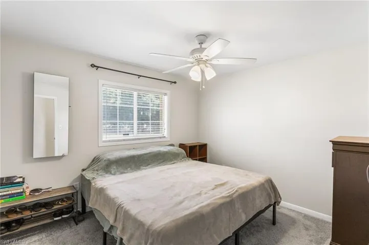 Carpeted bedroom featuring ceiling fan and baseboards