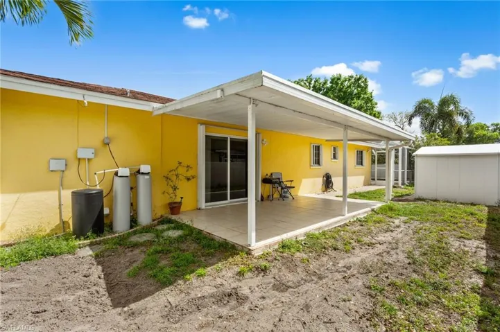 Back of house with stucco siding, a patio, and an outbuilding