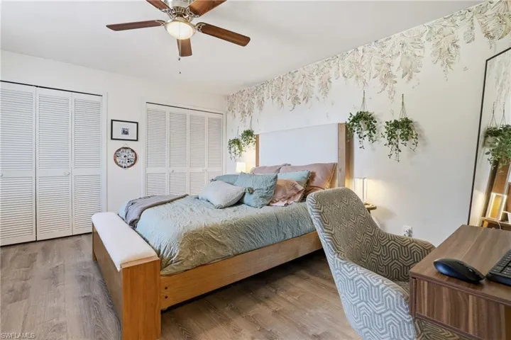 Bedroom featuring two closets, wood finished floors, and a ceiling fan