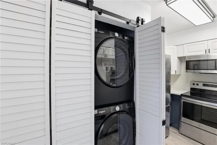 Laundry area featuring stacked washer / drying machine and a barn door