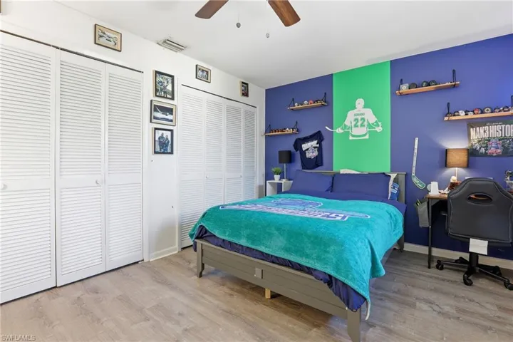 Bedroom with multiple closets, light wood-style floors, and a ceiling fan