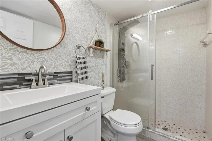 Bathroom with vanity, a stall shower, and wallpapered walls