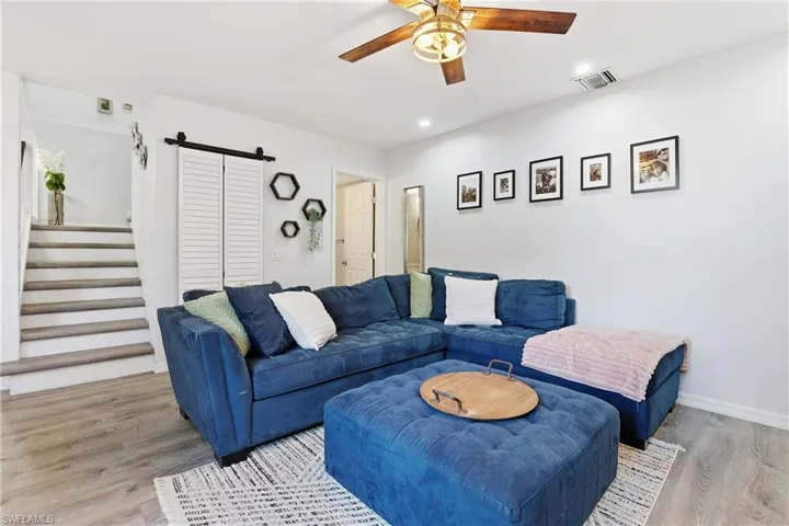 Living area with a barn door, light wood-style flooring, a ceiling fan, and recessed lighting