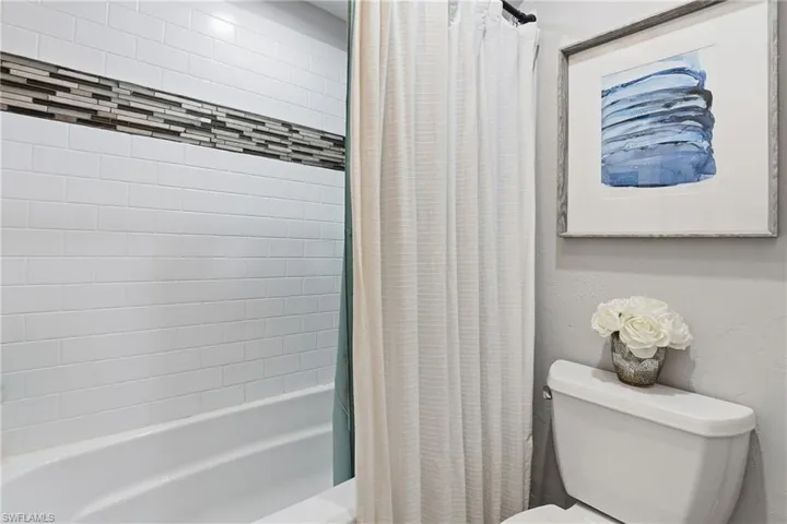 Full bathroom featuring toilet and shower / tub combo with curtain