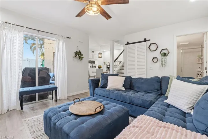 Living room featuring a barn door, wood finished floors, and ceiling fan