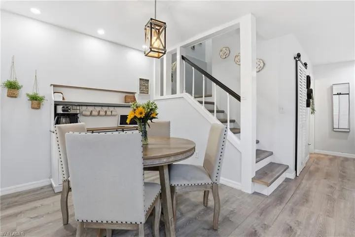 Dining area with light wood-style flooring, a barn door, and recessed lighting