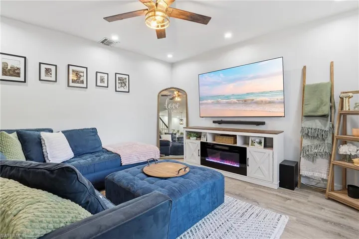 Living room featuring light wood finished floors, recessed lighting, a glass covered fireplace, and a ceiling fan