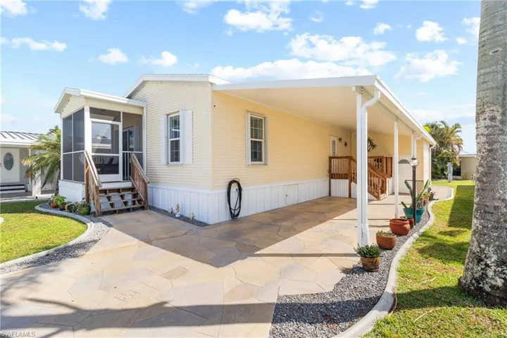 Manufactured / mobile home with a sunroom, a carport, and a front yard