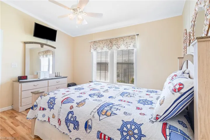 Bedroom featuring ceiling fan, crown molding, and light hardwood / wood-style flooring