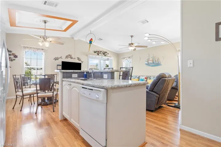 Kitchen featuring vaulted ceiling with beams, light hardwood / wood-style flooring, white dishwasher, sink, and white cabinetry
