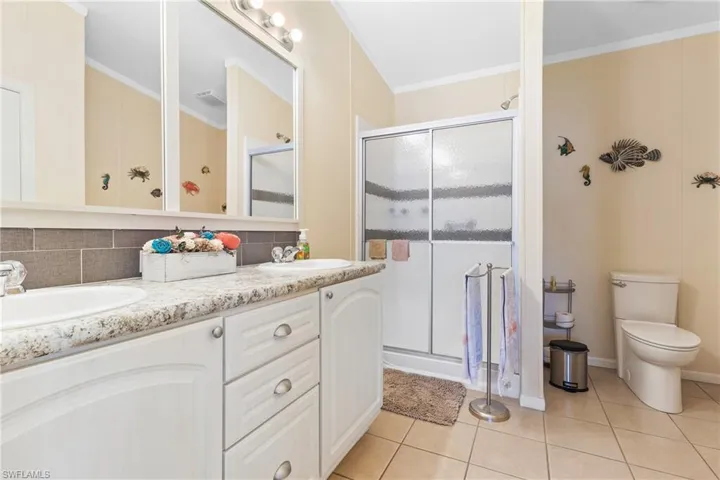 Bathroom with toilet, crown molding, vanity, an enclosed shower, and tasteful backsplash