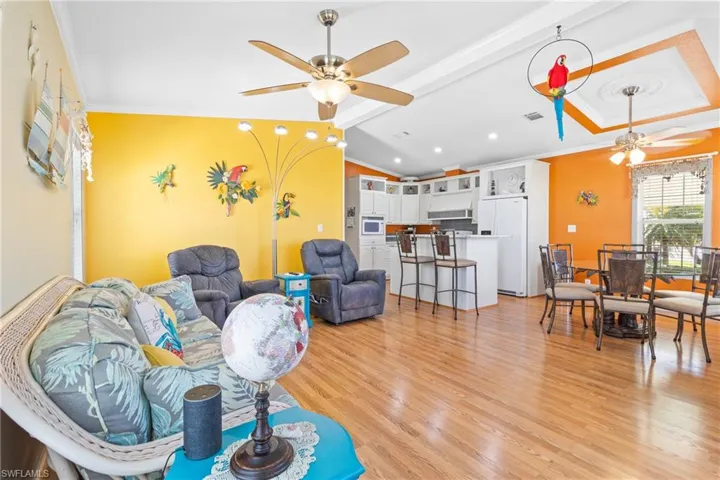 Living room with lofted ceiling with beams, light wood-type flooring, and ceiling fan