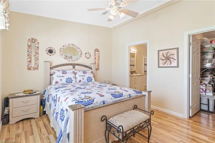 Bedroom with ensuite bathroom, light wood-type flooring, and ceiling fan
