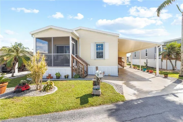 Manufactured / mobile home featuring a sunroom, a carport, and a front lawn