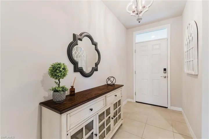 Entryway featuring tile flooring, a paneled door with transom, and a decorative ceiling light fixture
