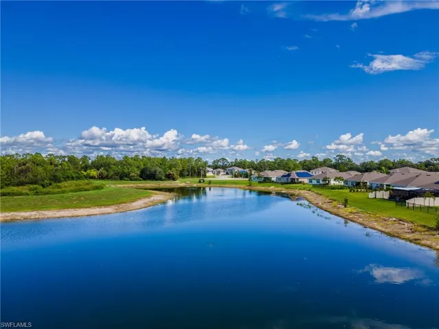Expansive water body with surrounding green spaces, residential structures, and natural tree lines