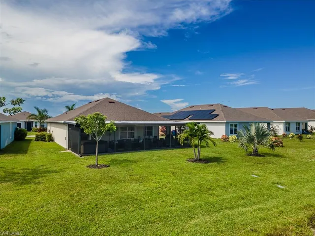 Expansive green lawn with established landscaping, screened-in patio, and a shingled roof
