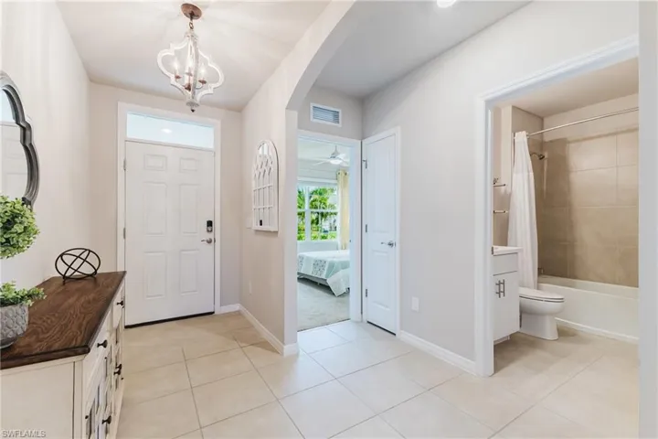 Foyer featuring tile flooring, a decorative chandelier, and a white paneled entry door with transom window