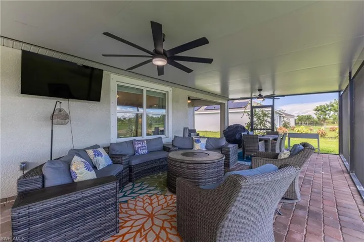Screened-in covered patio featuring a paver floor, dual ceiling fans, and a large window