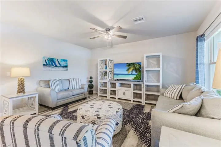 Bright living space featuring a ceiling fan, white walls, and wood-finish flooring