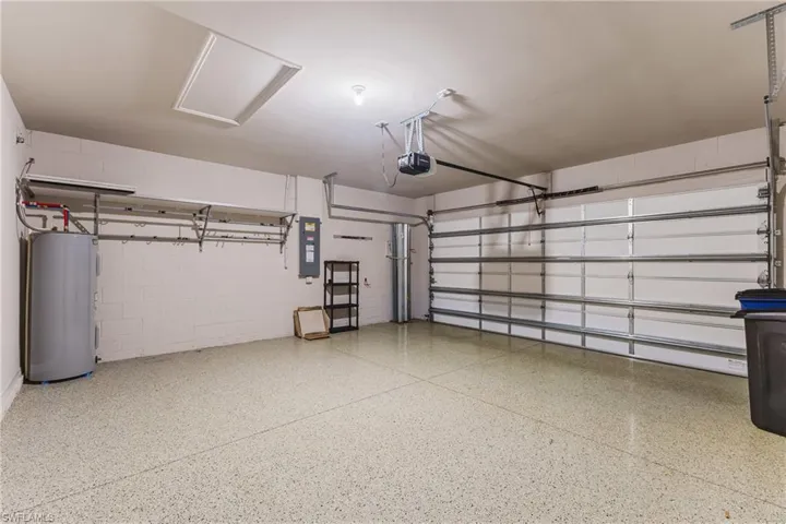 Attached garage with a finished floor, automatic garage door opener, and integrated wall shelving