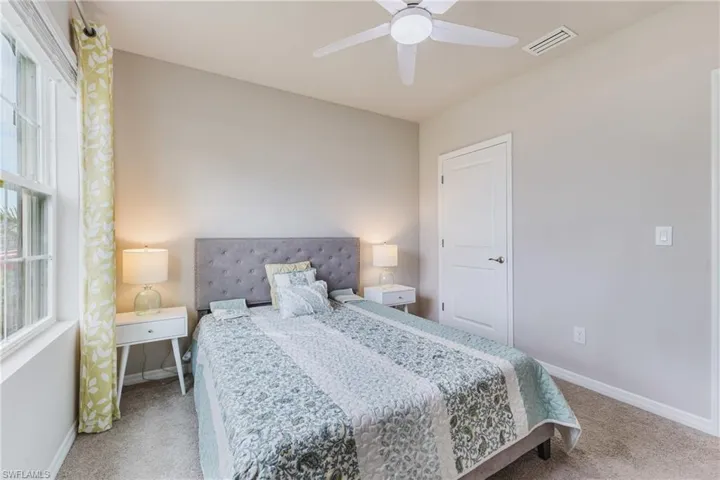 Vaulted ceiling, ceiling fan, window with vertical blinds, paneled door, and neutral-toned wall paint