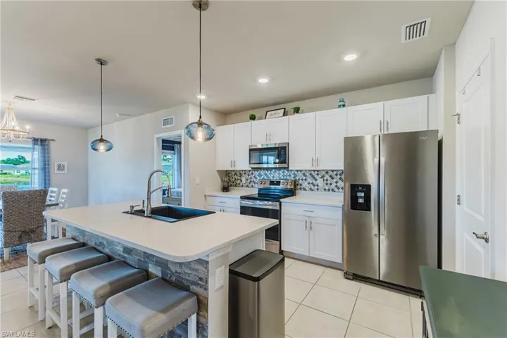 Kitchen featuring white cabinetry, stainless steel appliances, a center island with stone detailing, and pendant lighting