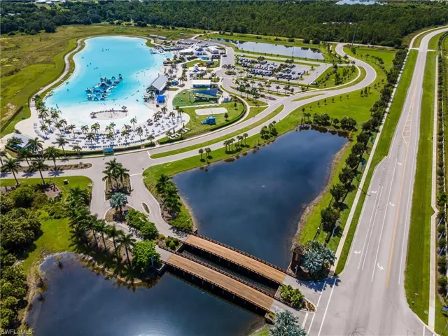 Expansive community with a large recreational lagoon, surrounding sand beach, and mature palm trees
