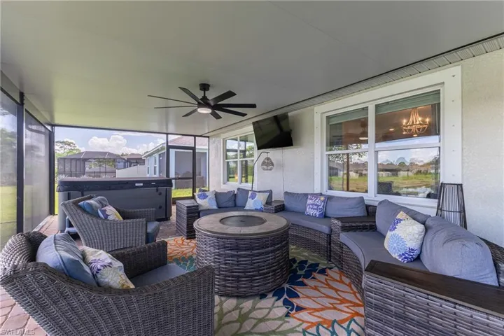 Screened patio featuring a ceiling fan, a built-in hot tub, and paver flooring