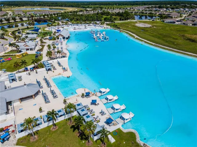 Expansive artificial lagoon with integrated water features, surrounding amenity buildings, dedicated lounging areas, and lush palm landscaping