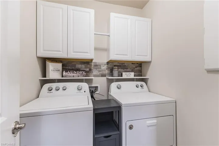 Dedicated laundry area with white cabinetry, wood-finish shelving, and a tiled backsplash