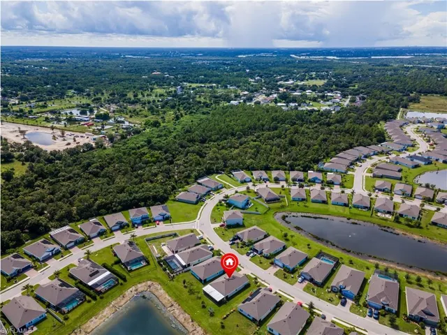 Residential community featuring a curved road layout, multiple water features, and surrounding natural foliage