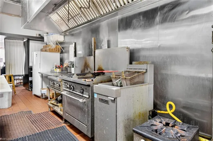 Kitchen with freestanding refrigerator, stainless steel range, high end range, wall chimney exhaust hood, and wood finished floors