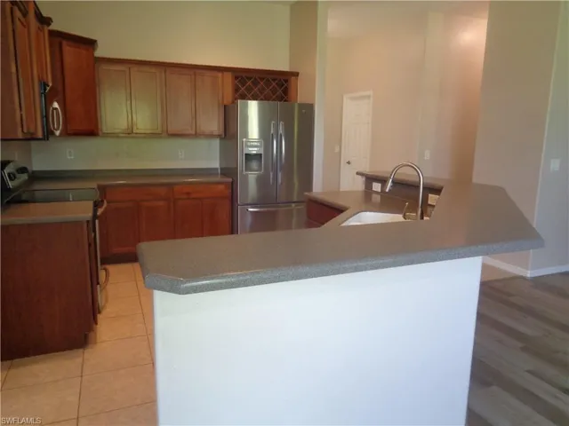 Kitchen with stainless steel appliances, light brown cabinetry, Corian countertops, and kitchen island