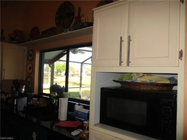 Kitchen view of black microwave and dark stone counters