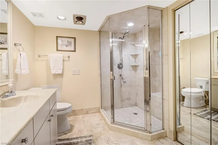 Full bathroom featuring vanity, a stall shower, light marble finish flooring, and recessed lighting