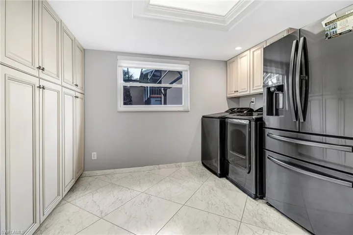 Washroom featuring washer and clothes dryer and light marble finish floors