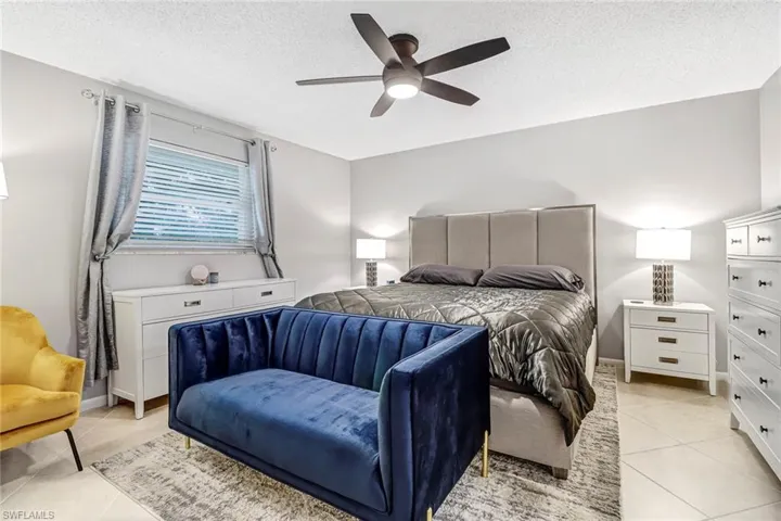 Bedroom with light tile patterned floors, a textured ceiling, and a ceiling fan