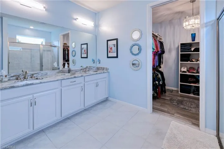 primary ensuite with double sink vanity and huge walk-in closet with custom shelving