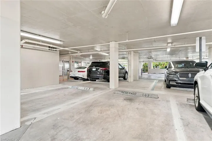 Underground parking garage featuring concrete flooring, overhead fluorescent lighting, and designated parking spaces
