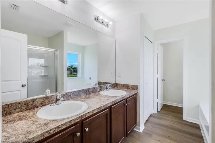 Bathroom with dual vanity, a tub to relax in, and hardwood / wood-style floors