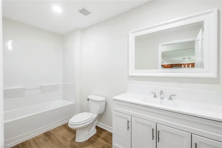 Full bathroom featuring vanity, toilet, shower / washtub combination, and hardwood / wood-style floors